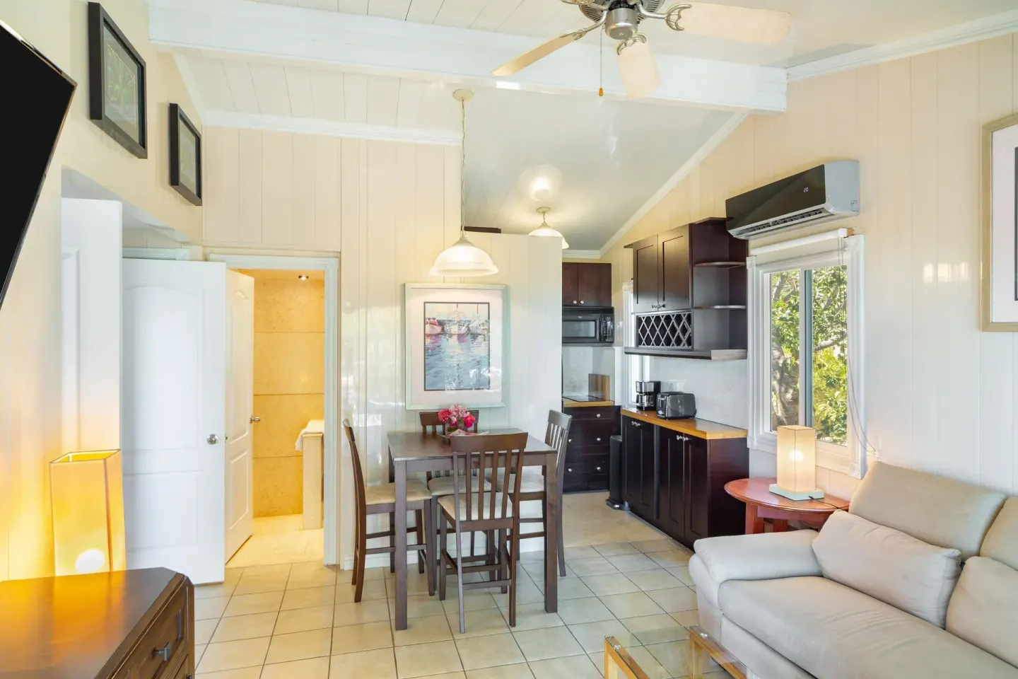 Suite kitchenette and dining area with sofa by the window at Kokomo Botanical Resort.