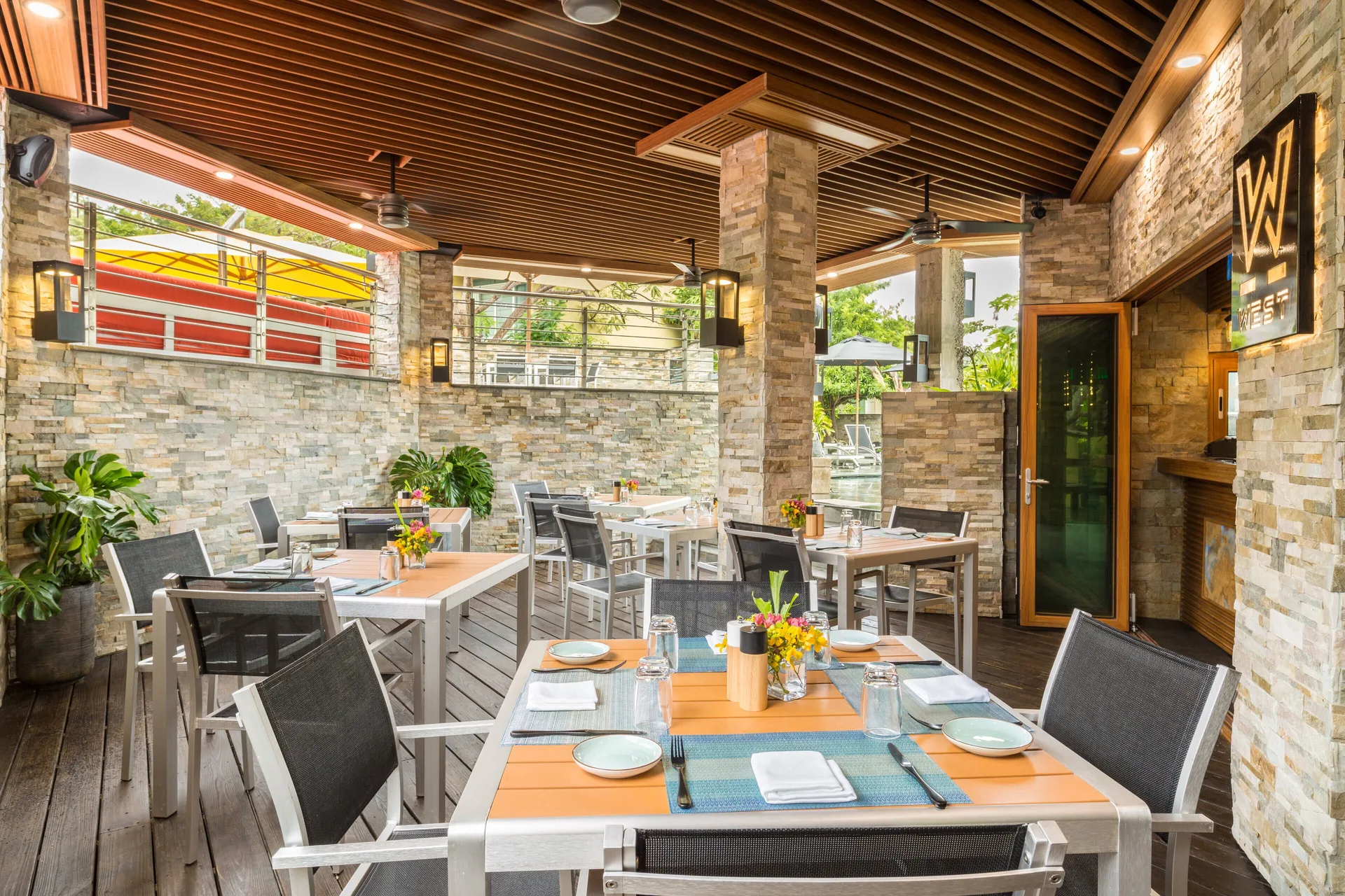 Open-air WE Market Cafe dining terrace with set tables at Kokomo Botanical Resort.