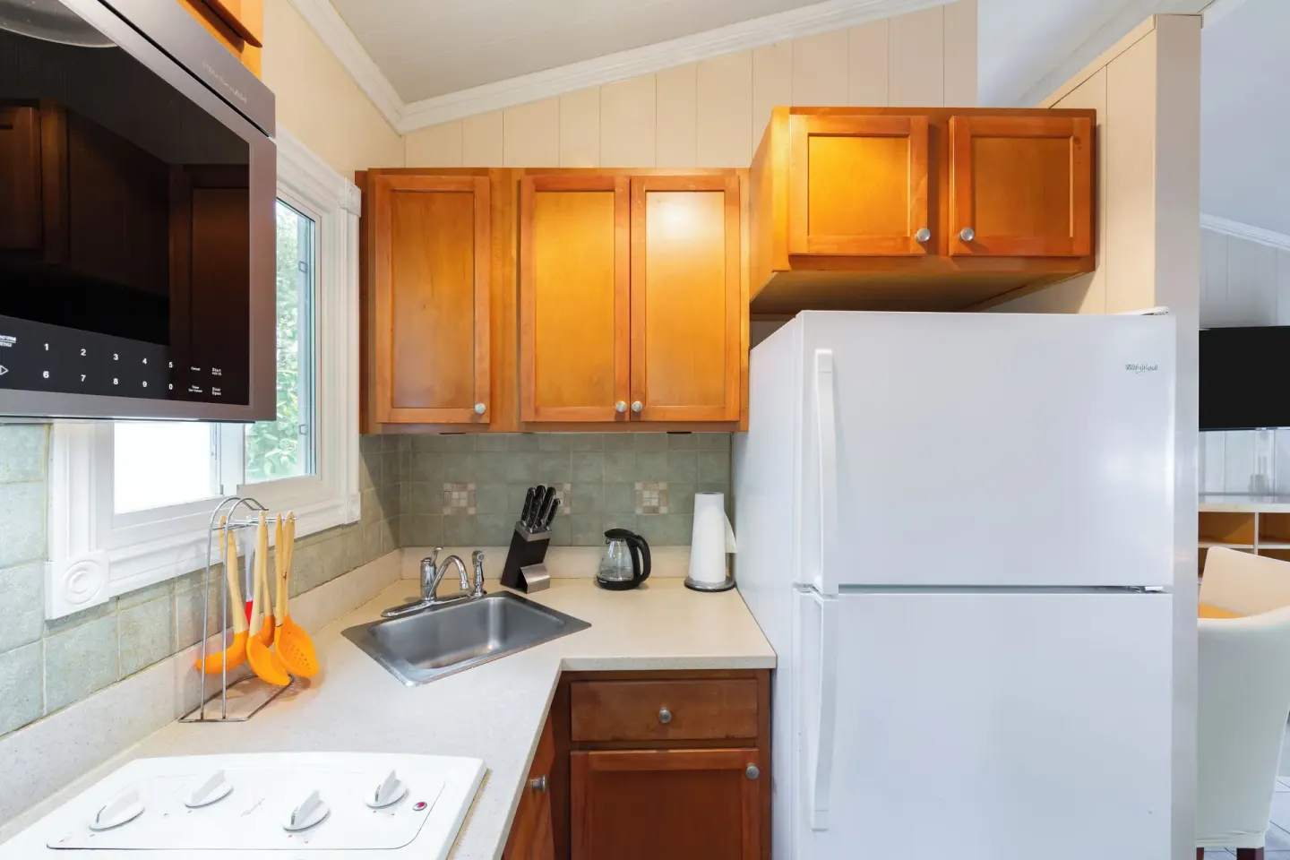 Compact cottage kitchen with refrigerator and sink at Kokomo Botanical Resort.