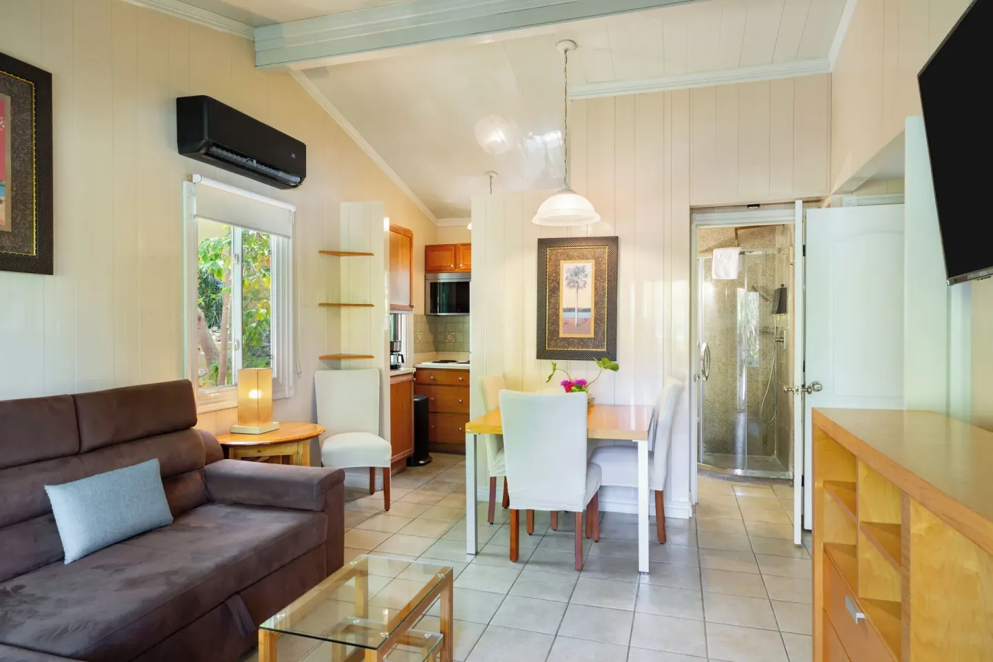 Living and dining area with kitchenette and shower beyond at Kokomo Botanical Resort.