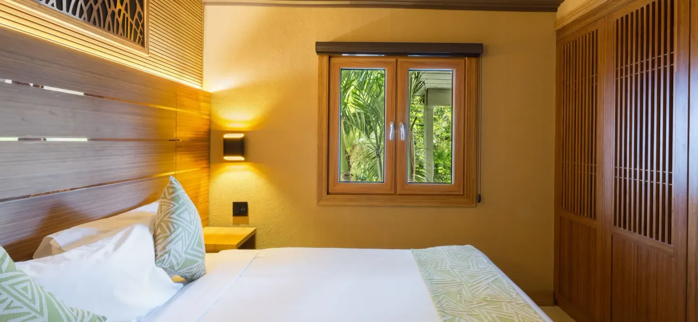 Superior Cottage bedroom with bed, garden window, and wood wardrobe at Kokomo Botanical Resort.