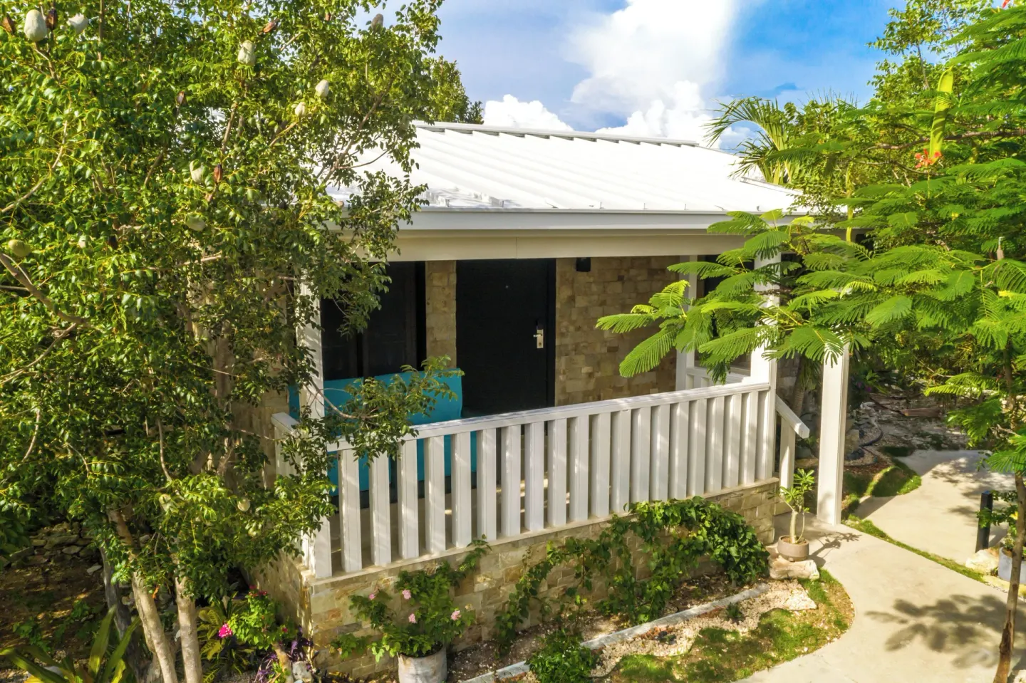 Superior Cottage exterior with white porch railing and garden plants at Kokomo Botanical Resort.