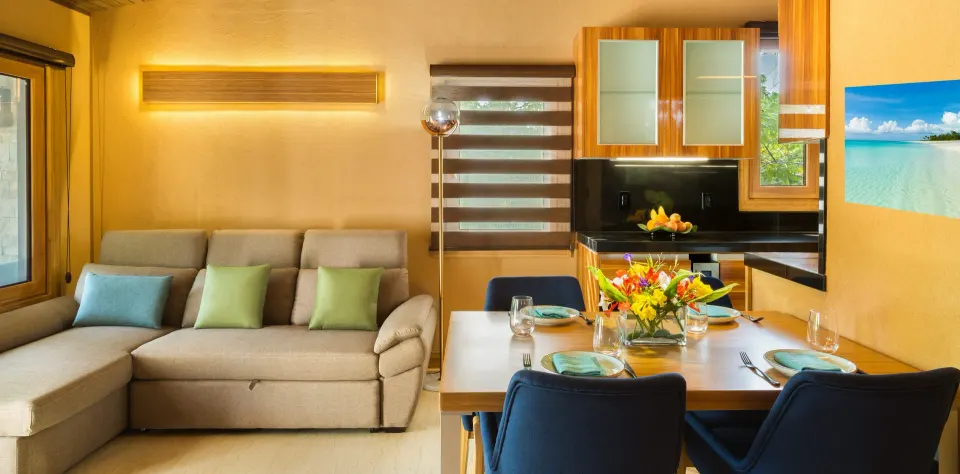 Superior Cottage living area with sofa, dining table, and kitchen at Kokomo Botanical Resort.