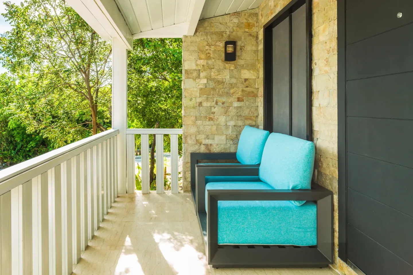 Superior Cottage porch with turquoise cushioned chairs at Kokomo Botanical Resort.