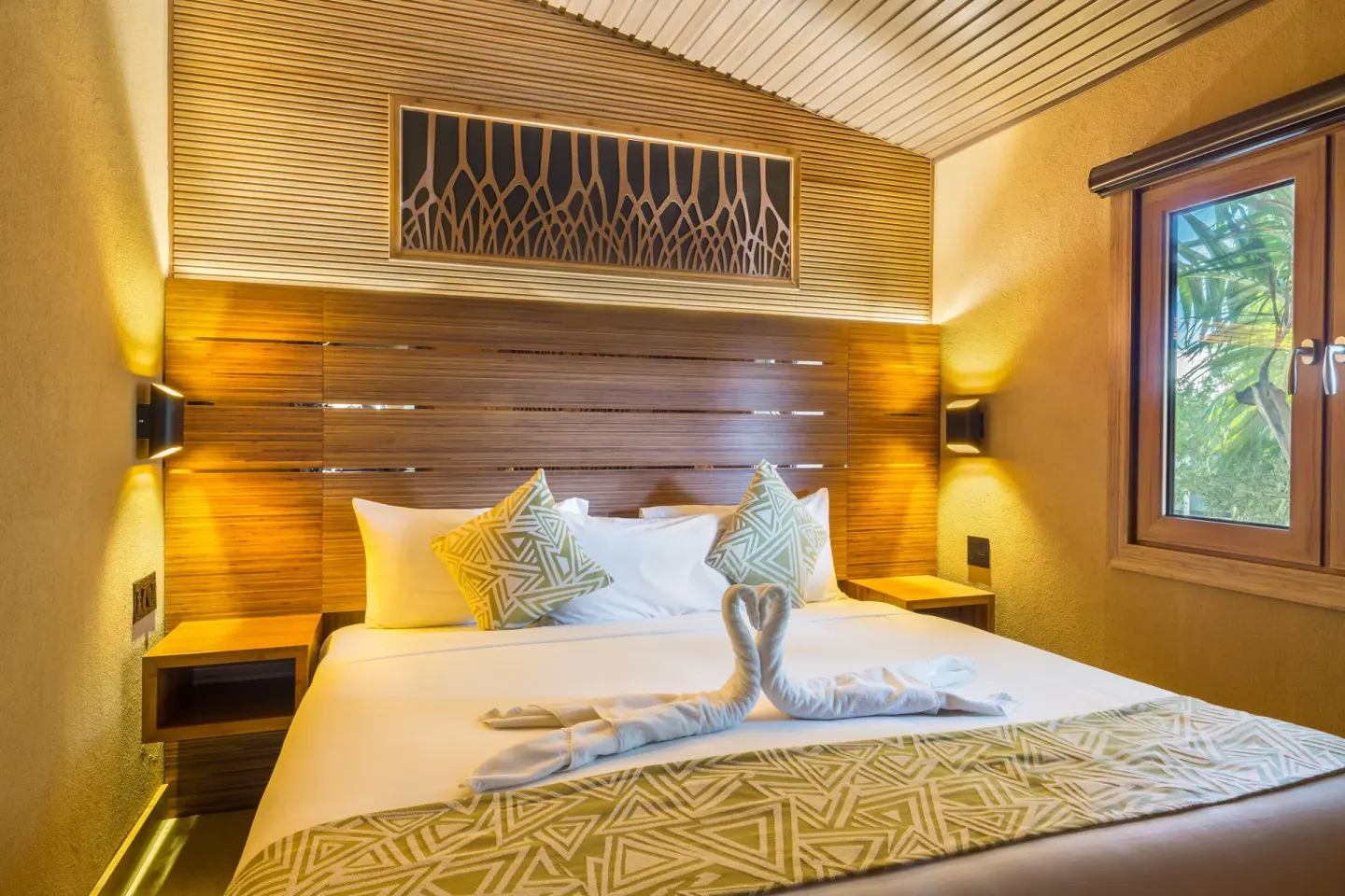 Superior Cottage bedroom with white bed and towel swans at Kokomo Botanical Resort.