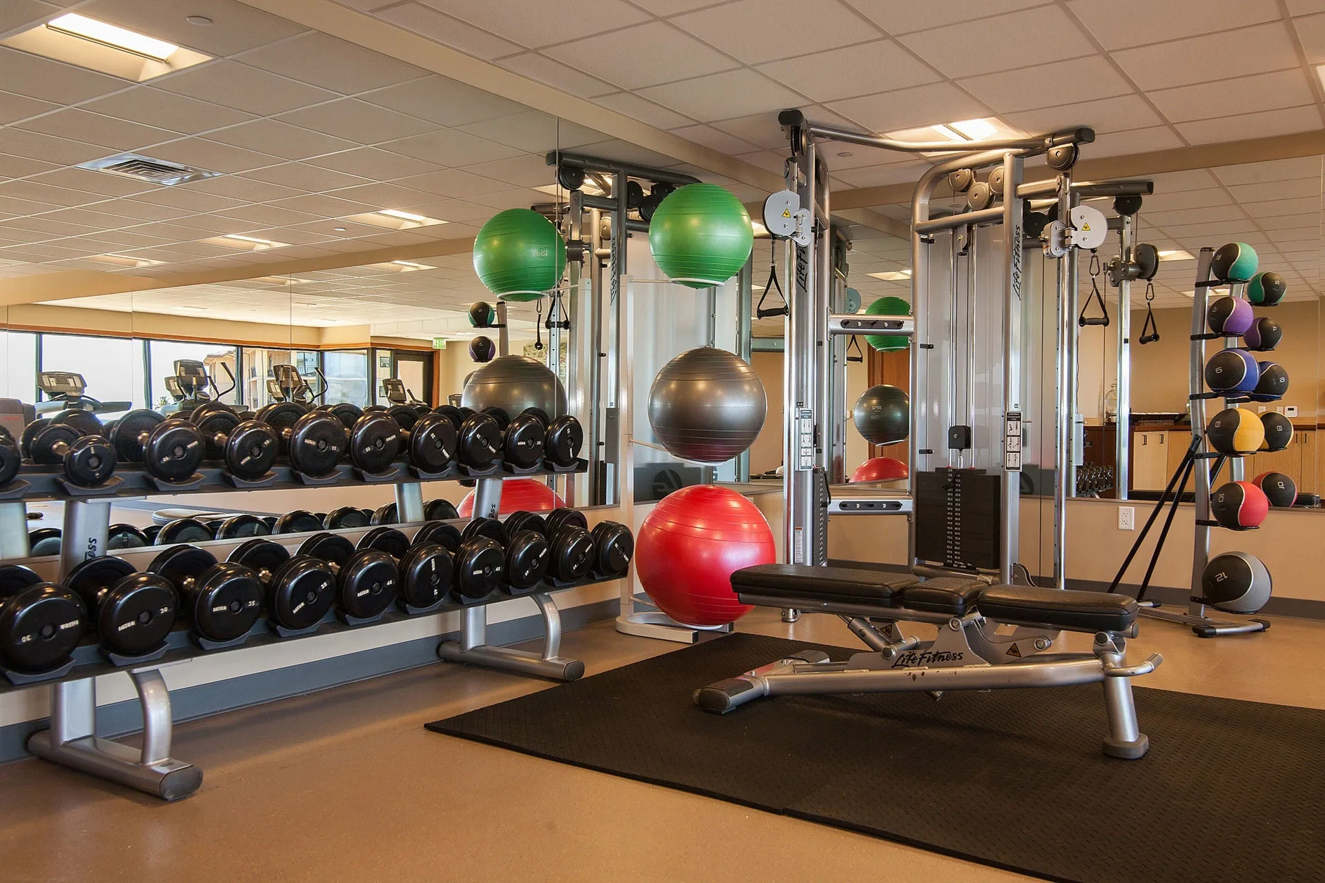 Fitness center with dumbbells, cable machines, and exercise balls at Koloa Landing Resort at Poipu.
