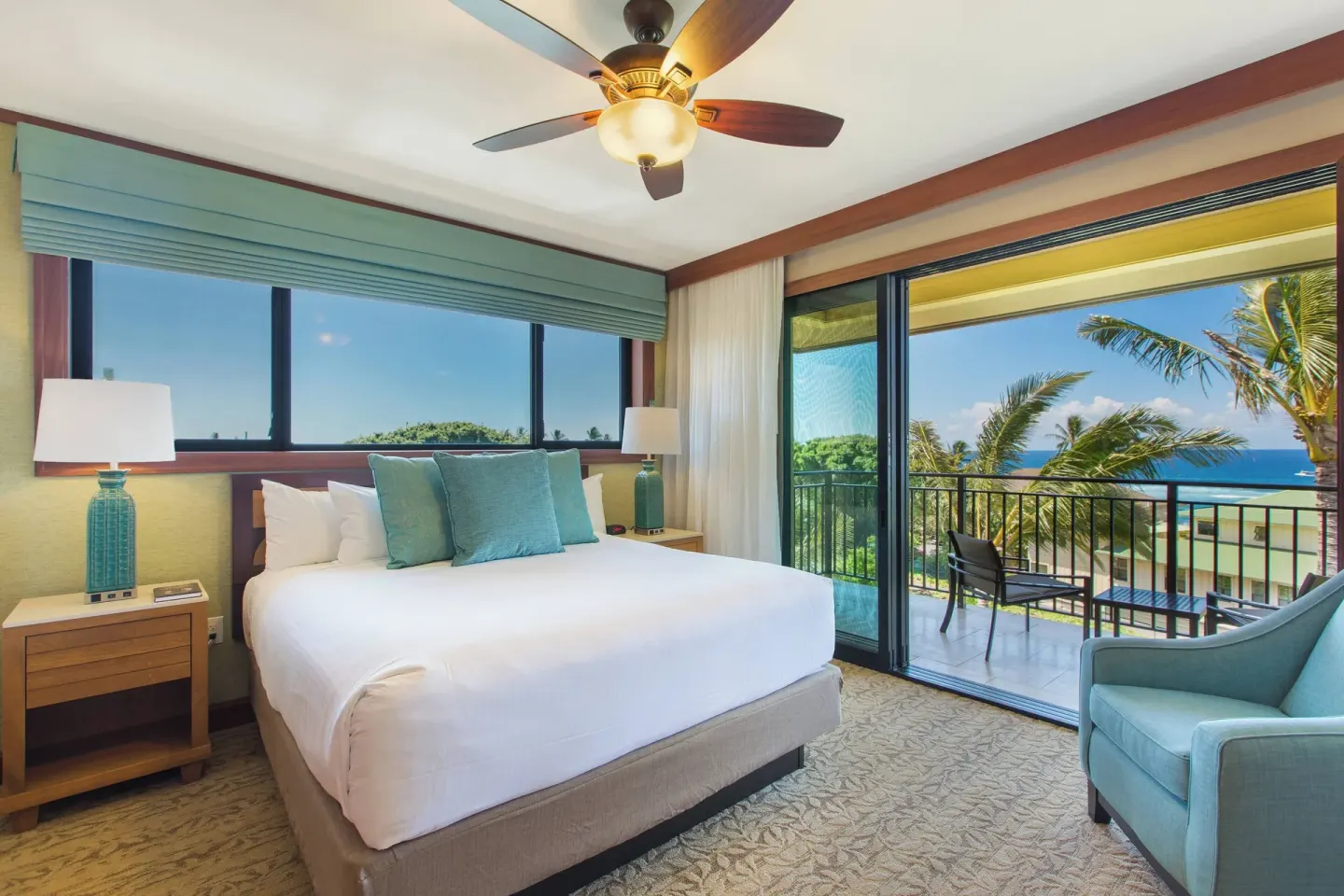King bedroom with blue accents and ocean balcony at Koloa Landing Resort at Poipu.