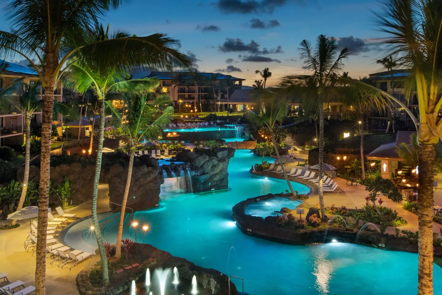 Illuminated resort pool and palm trees at Koloa Landing Resort at Poipu at dusk.