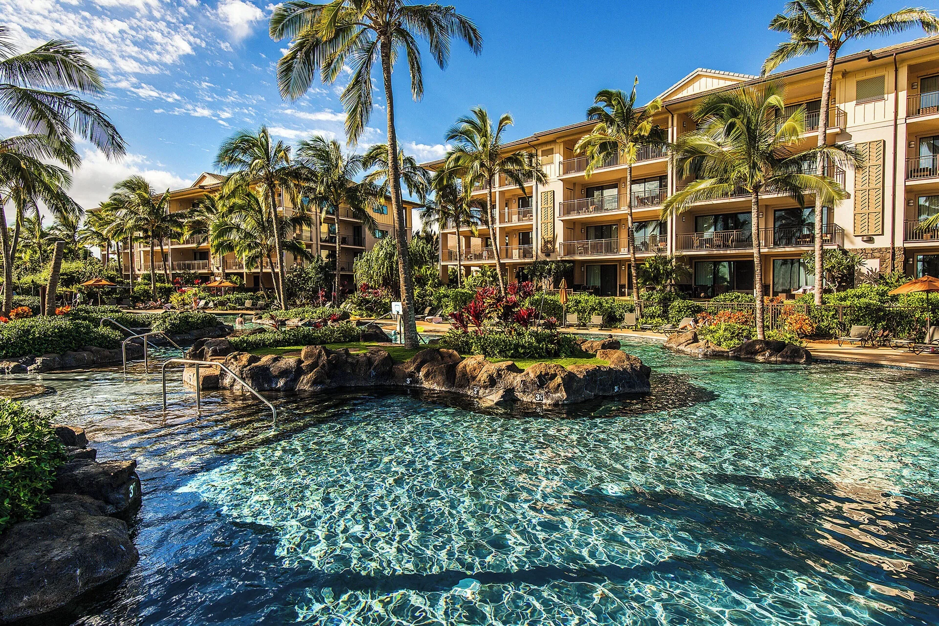 Swimming pool with lava rock edges and guest buildings at Koloa Landing Resort at Poipu.