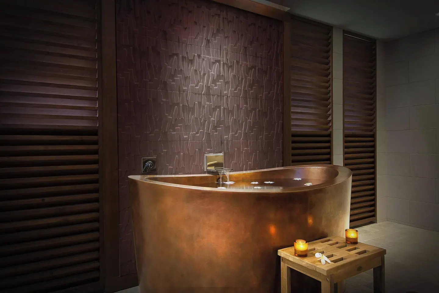 Spa soaking tub with candles, wood shutters, and textured wall at Koloa Landing Resort at Poipu.