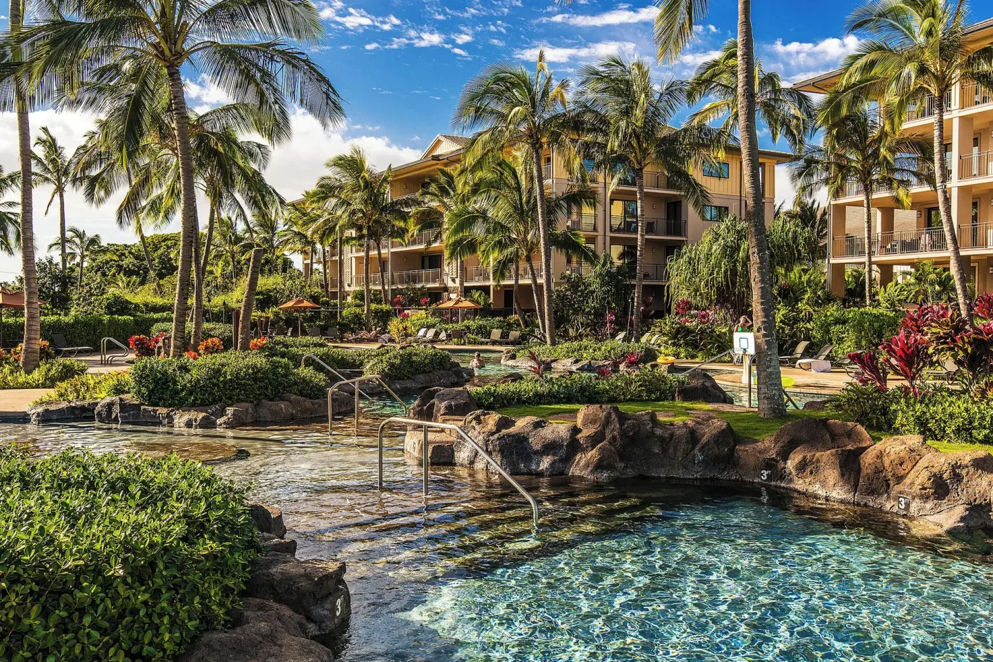 Tropical pool area with rock edges and palms beside guest buildings at Koloa Landing Resort at Poipu.