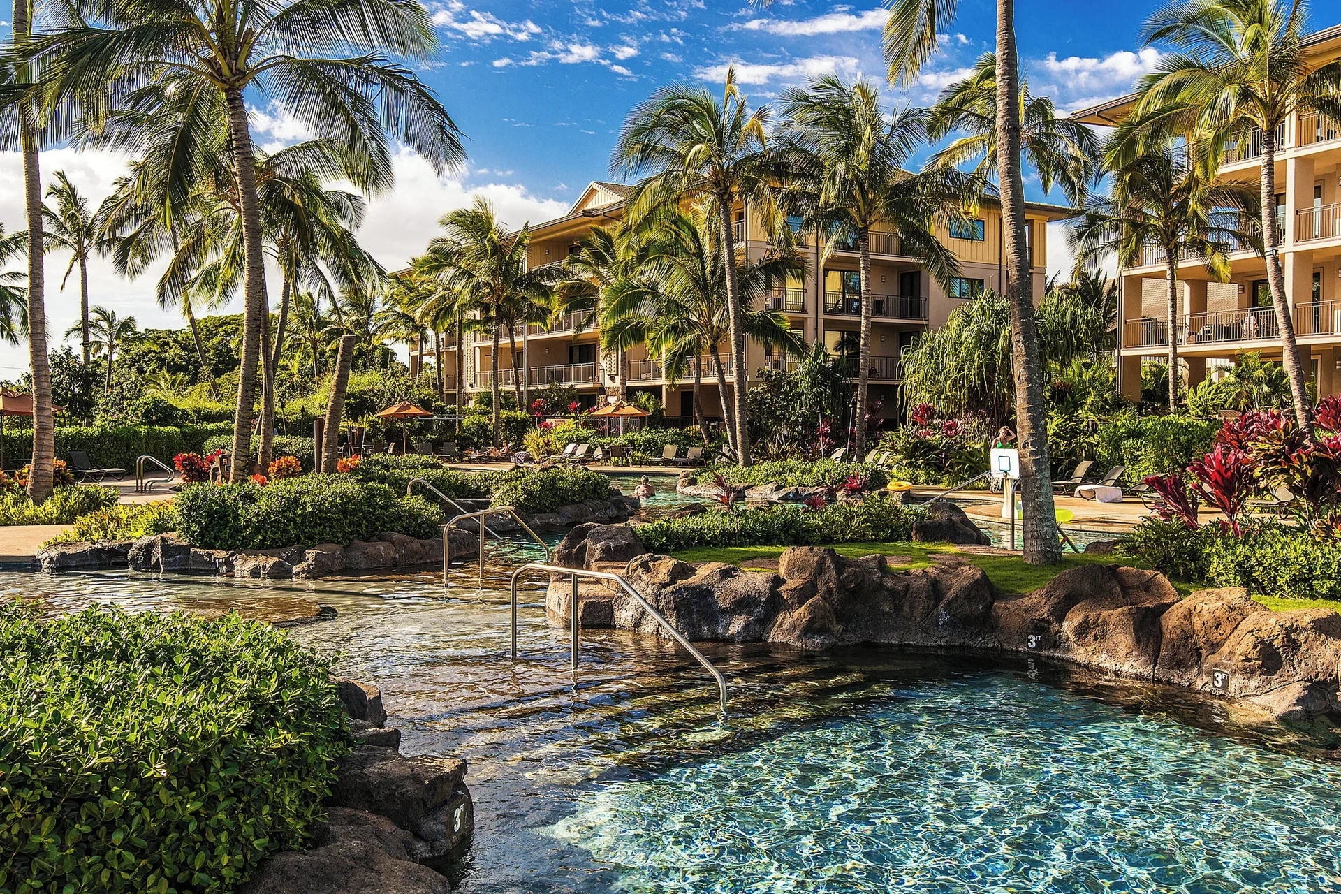 Tropical pool area with rock edges and palms beside guest buildings at Koloa Landing Resort at Poipu.