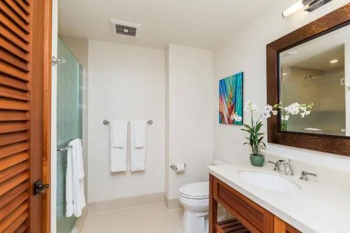 Studio bathroom with towels, toilet, and wood vanity at Koloa Landing Resort at Poipu.