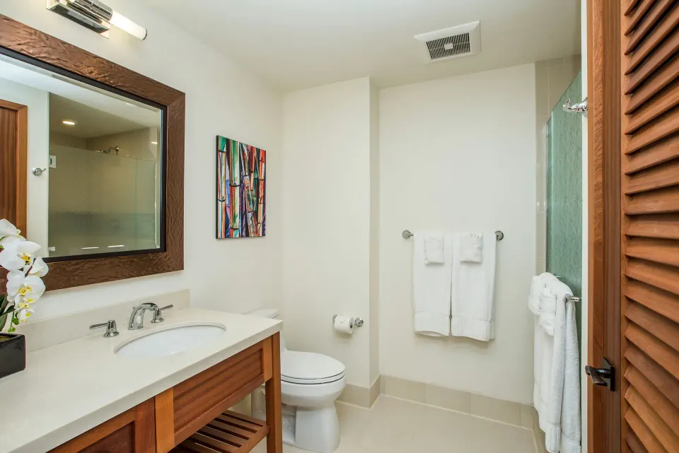 Studio bathroom with vanity, mirror, toilet and shower area at Koloa Landing Resort at Poipu.