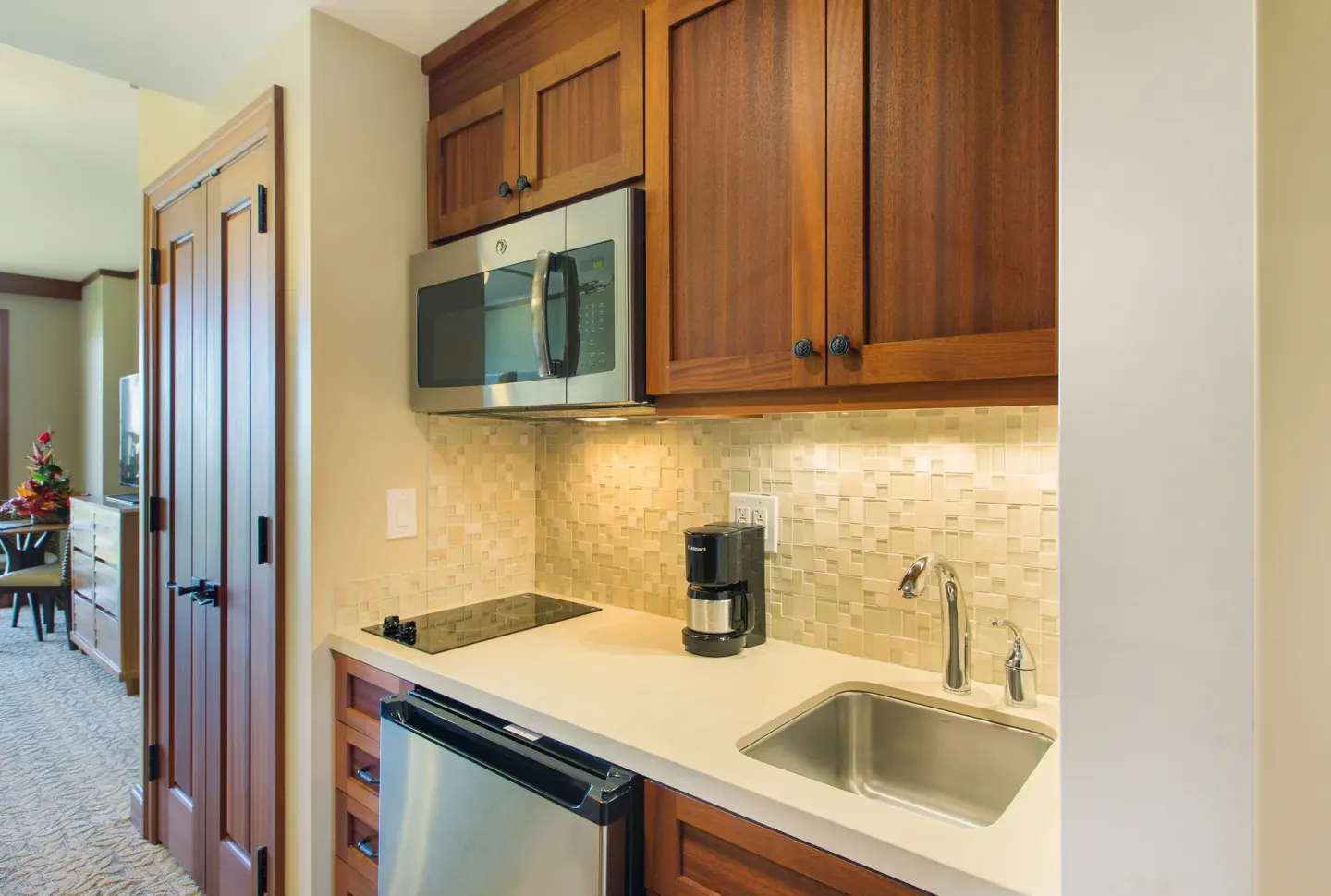 Studio kitchenette with sink, cooktop, microwave and wood cabinets at Koloa Landing Resort at Poipu.