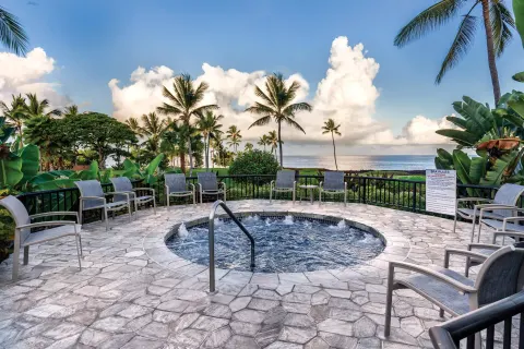 Circular bubbling spa with lounge chairs, palms, and ocean view at Kona Coast Resort.