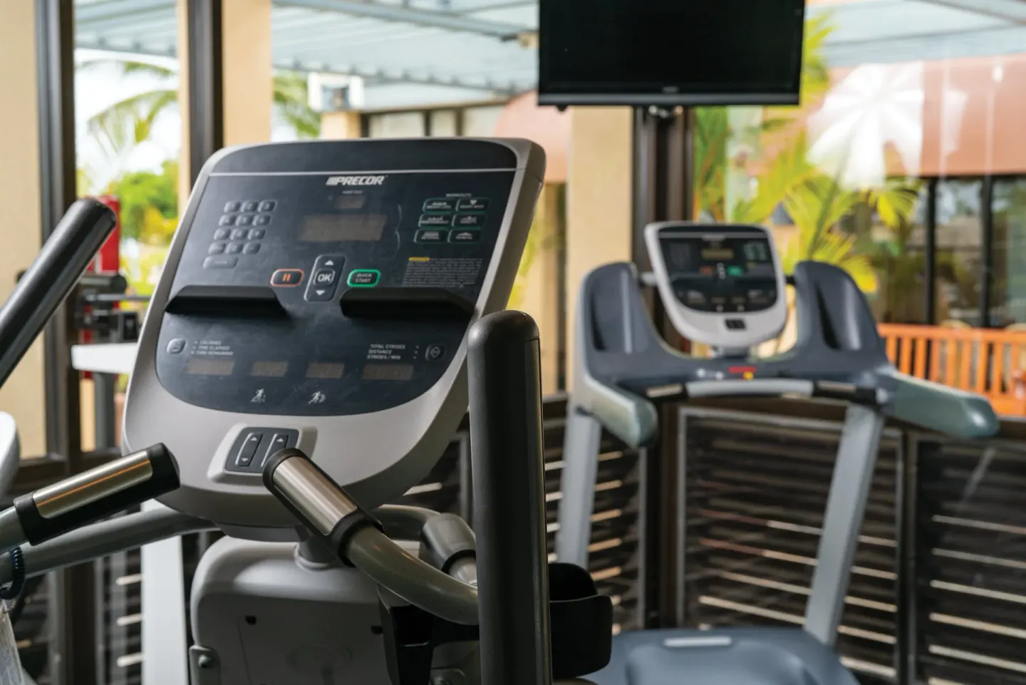 Cardio equipment and a wall-mounted TV in the fitness room at Kona Coast Resort.