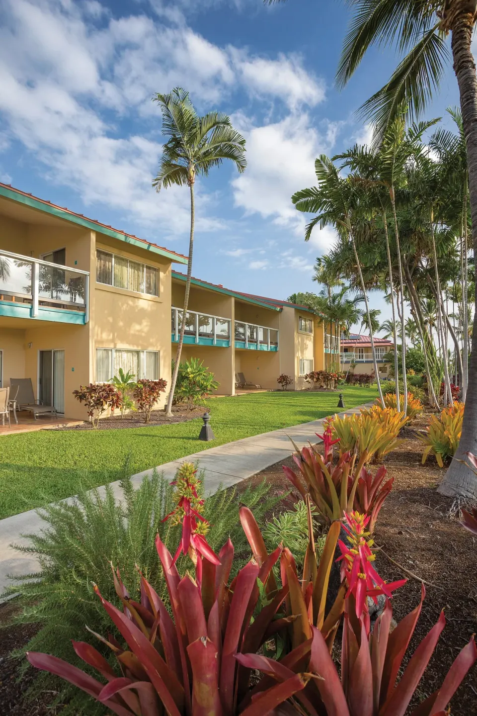 Guest buildings and tropical landscaping along a walkway at Kona Coast Resort.
