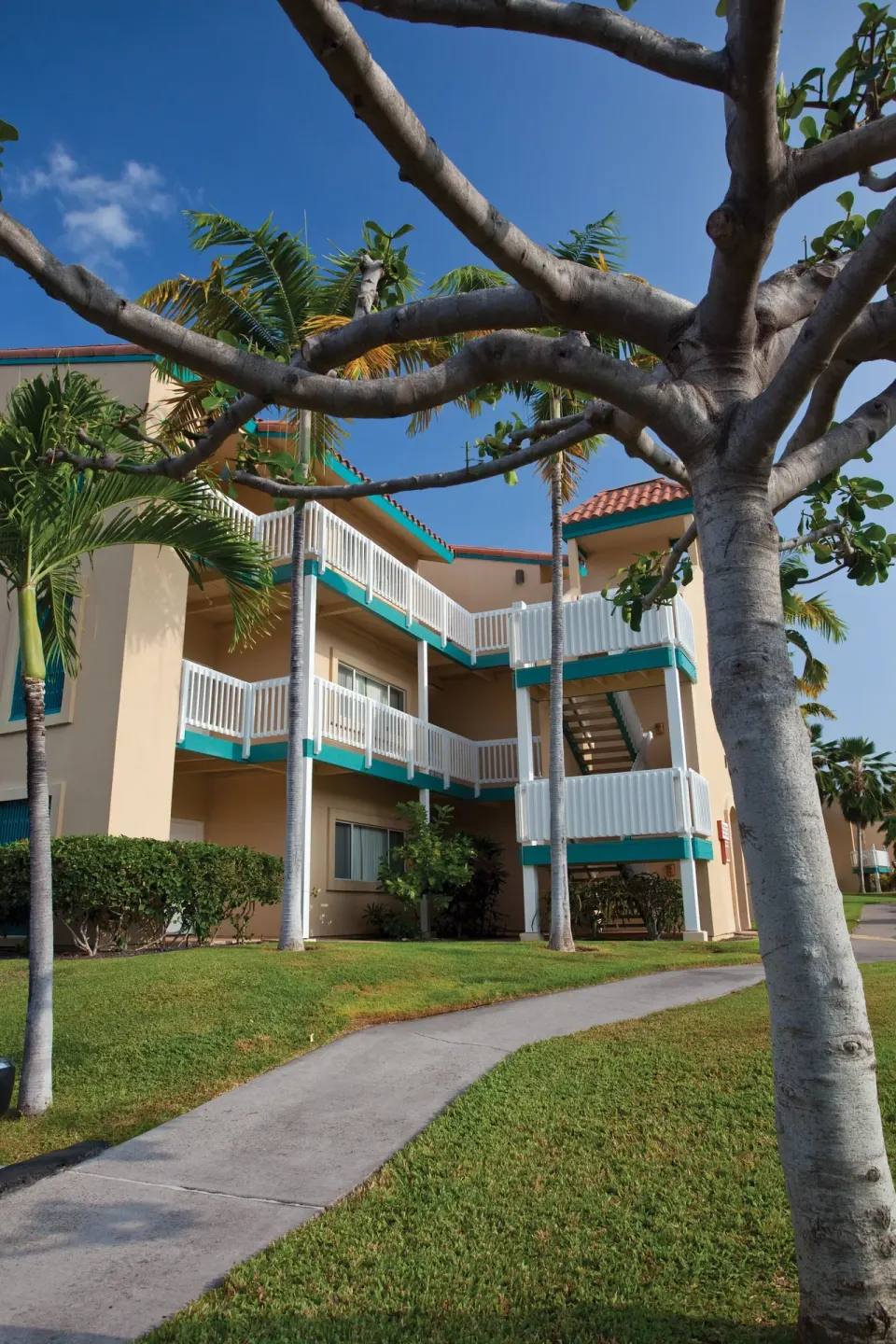 Resort buildings with balconies and exterior stairs stand behind lawns at Kona Coast Resort.
