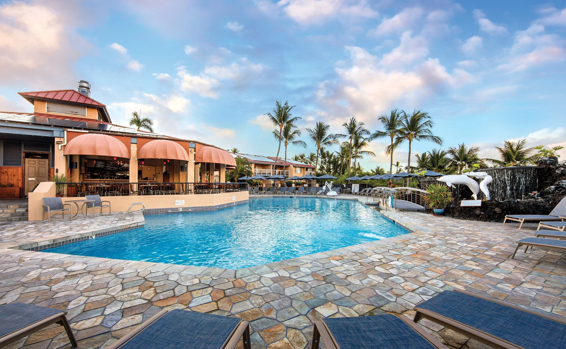 Main pool with loungers, palms, and terrace seating at Kona Coast Resort.