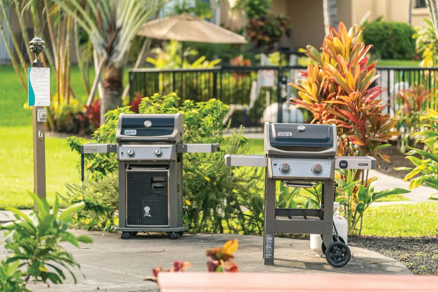 Two outdoor gas grills stand in a landscaped barbecue area at Kona Coast Resort.