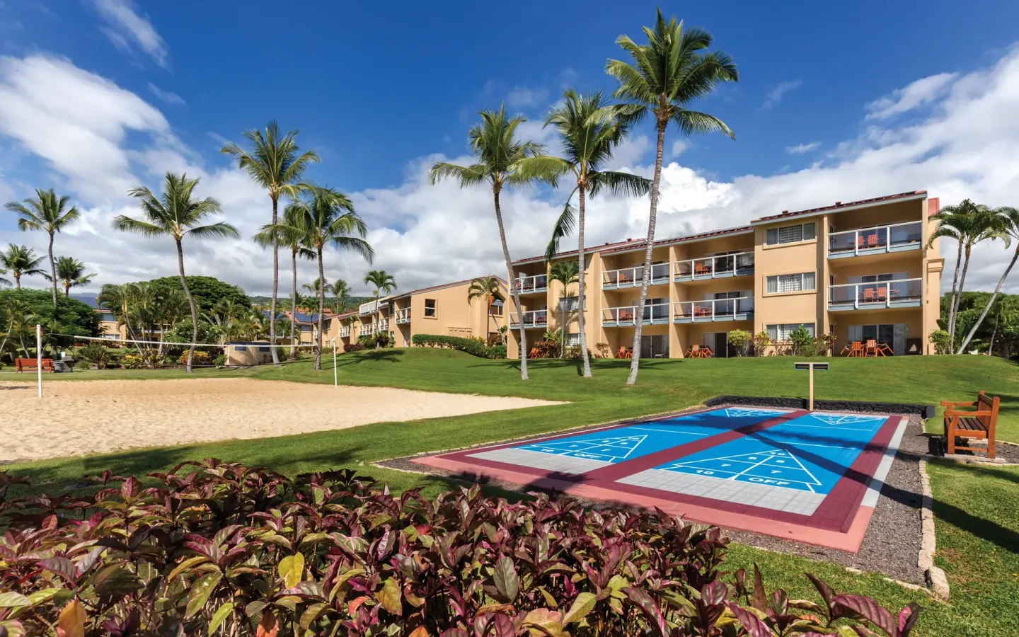 Shuffleboard and sand volleyball courts beside guest buildings at Kona Coast Resort.