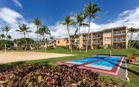 Shuffleboard and sand volleyball courts beside guest buildings at Kona Coast Resort.