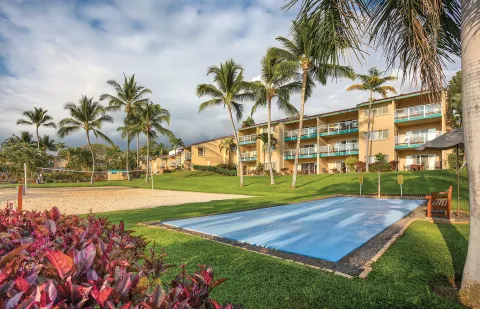 Sand volleyball court, blue game court, palms, and resort buildings at Kona Coast Resort.