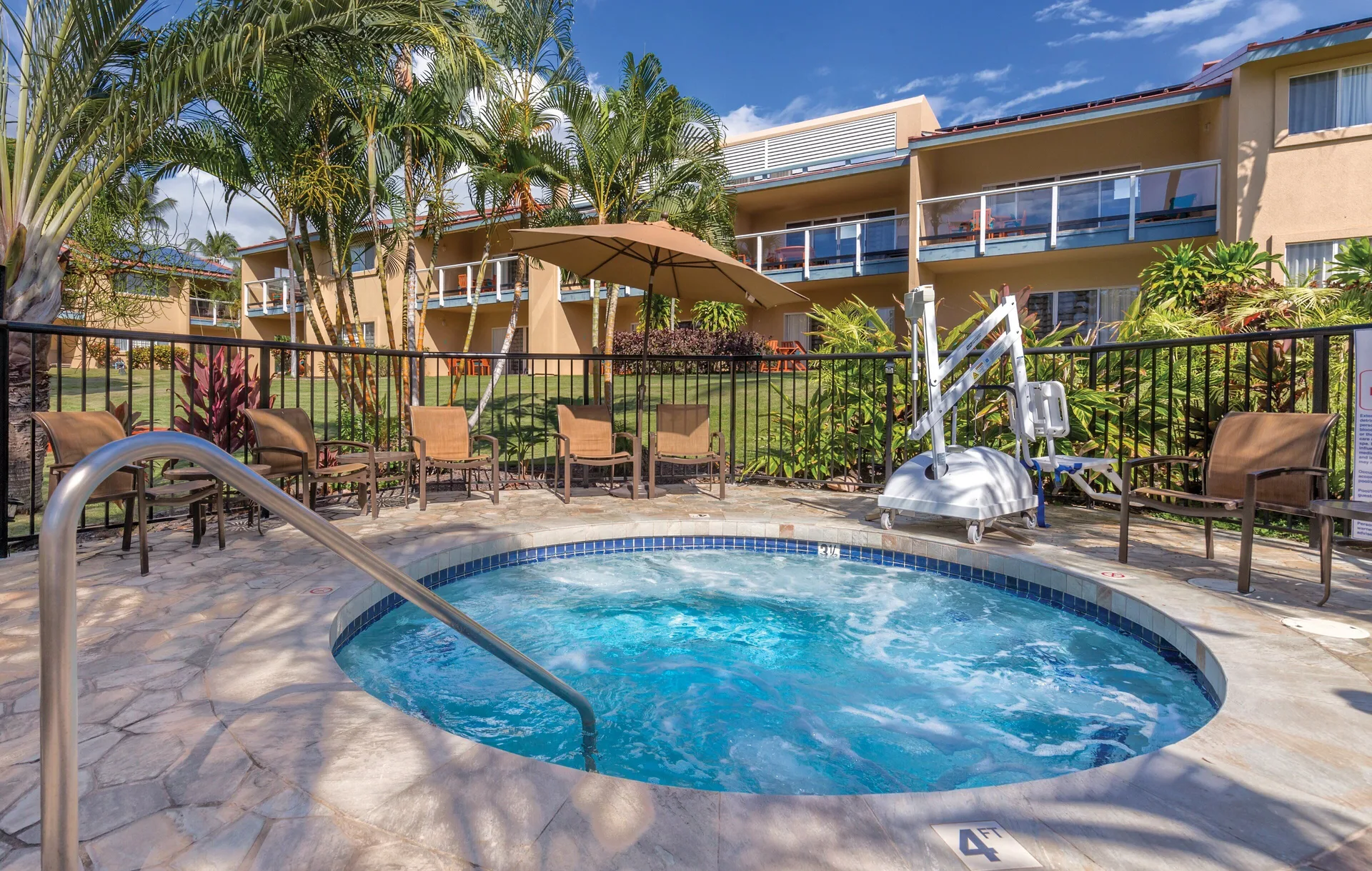 Round spa tub with chairs, palms, and resort buildings at Kona Coast Resort.