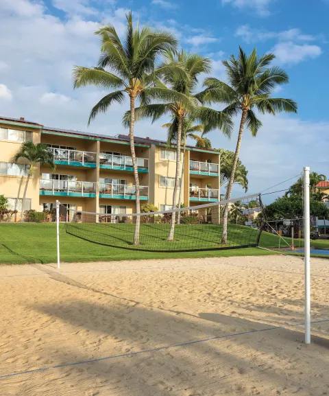 Sand volleyball court with palms and balconies behind it at Kona Coast Resort.