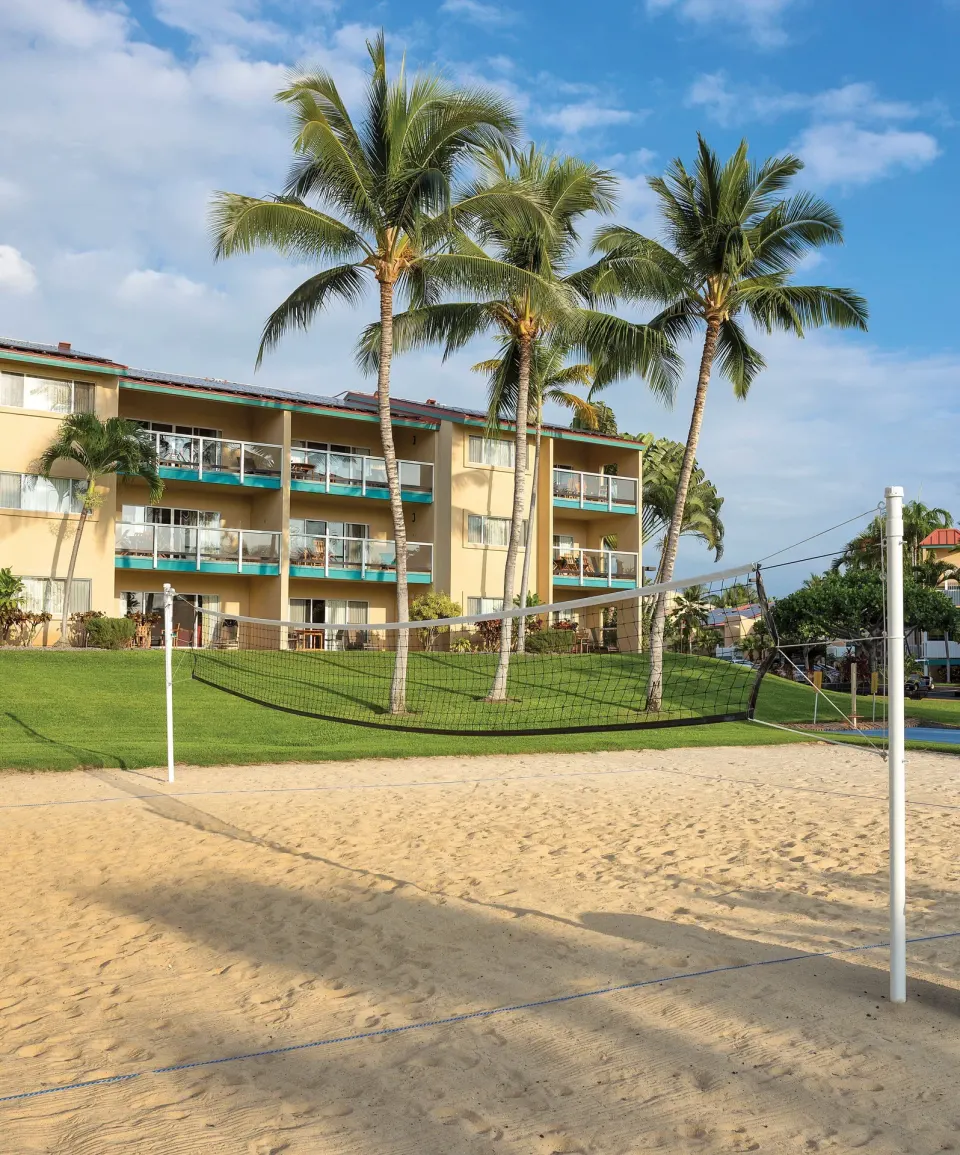 Sand volleyball court with palms and balconies behind it at Kona Coast Resort.