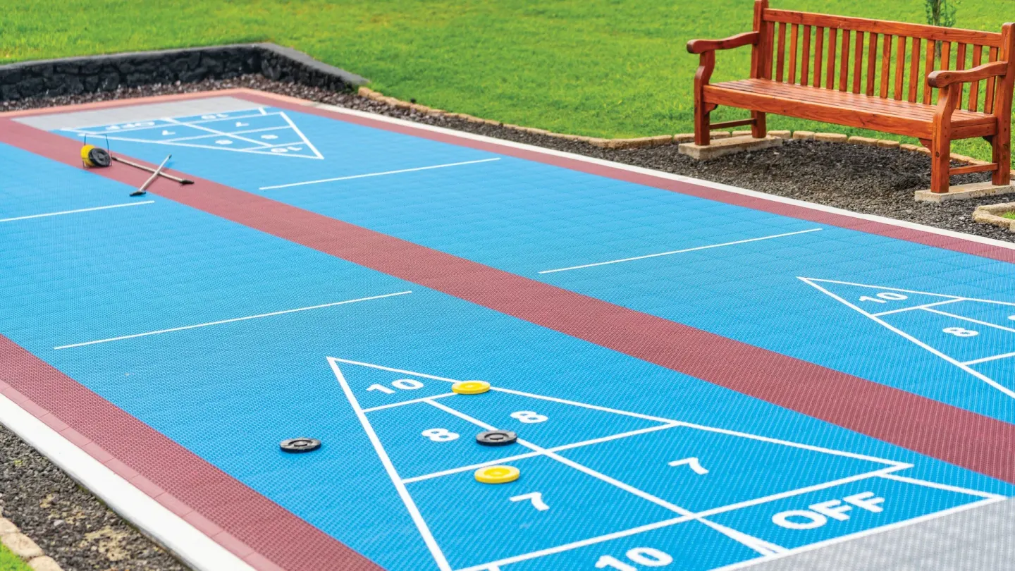 Close-up of blue shuffleboard courts with cues and discs at Kona Coast Resort.