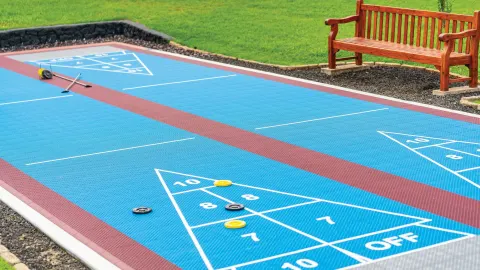 Close-up of blue shuffleboard courts with cues and discs at Kona Coast Resort.