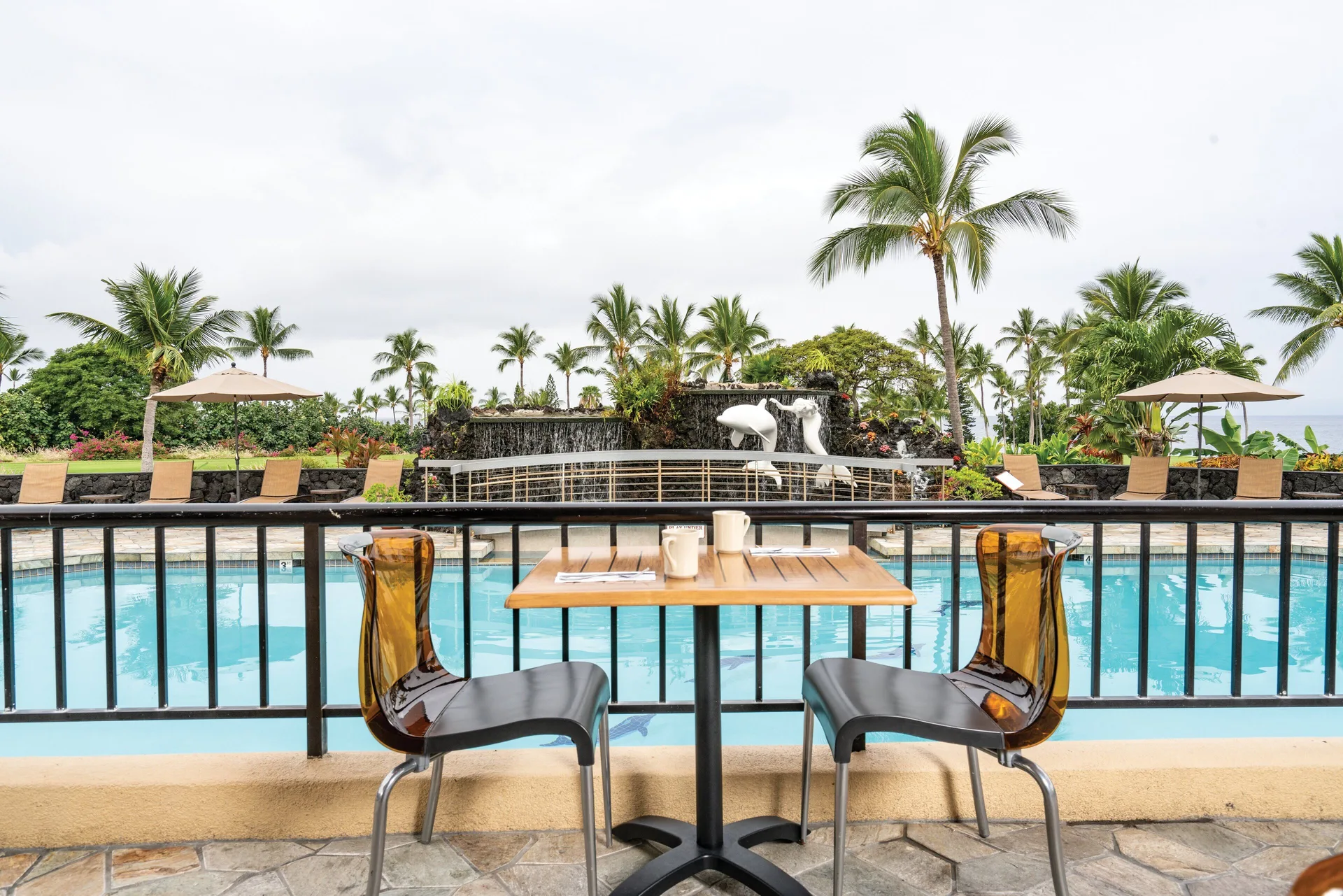 Poolside table for two beside the swimming pool and waterfall at Kona Coast Resort.