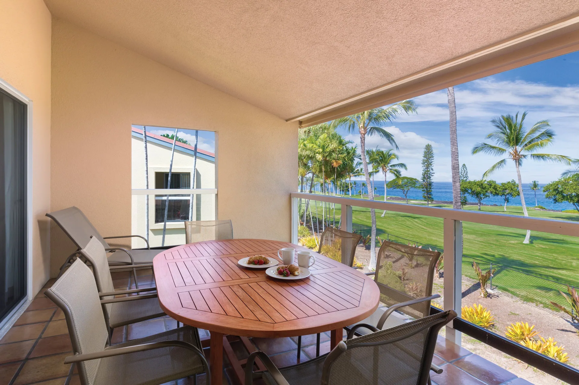 One Bedroom Villa Honu balcony dining area with ocean and palms at Kona Coast Resort.