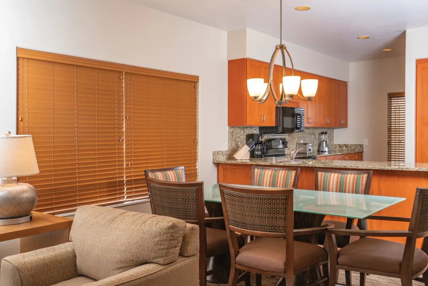 One Bedroom Villa Honu dining area and kitchen at Kona Coast Resort with glass table and wood cabinetry.