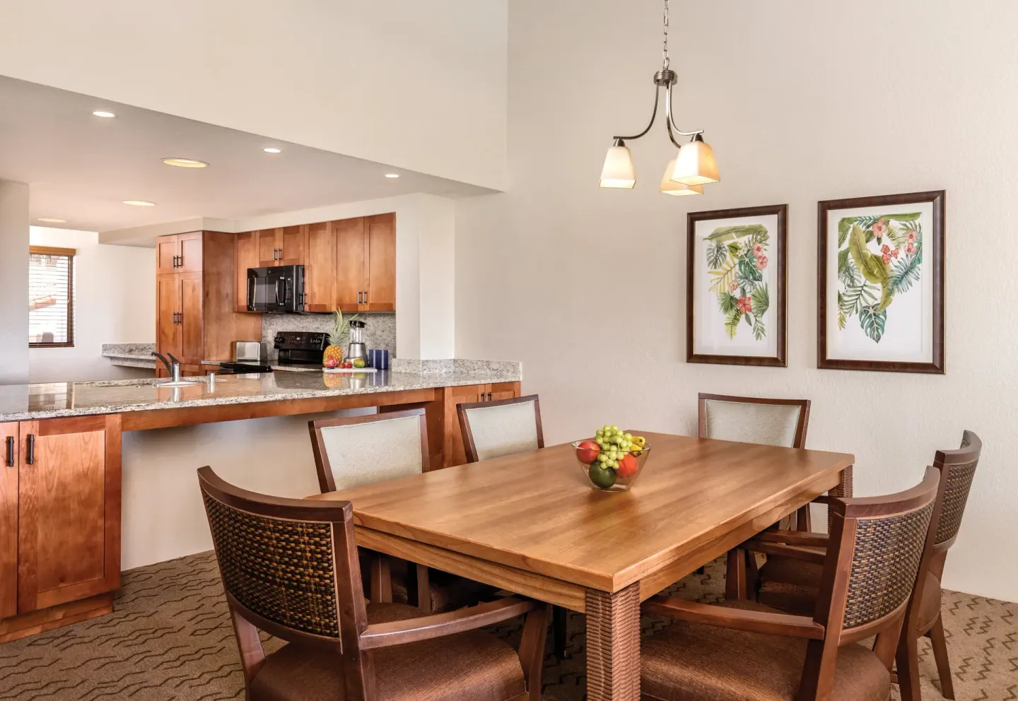 One Bedroom Villa Honu dining table and open kitchen at Kona Coast Resort with tropical wall art.