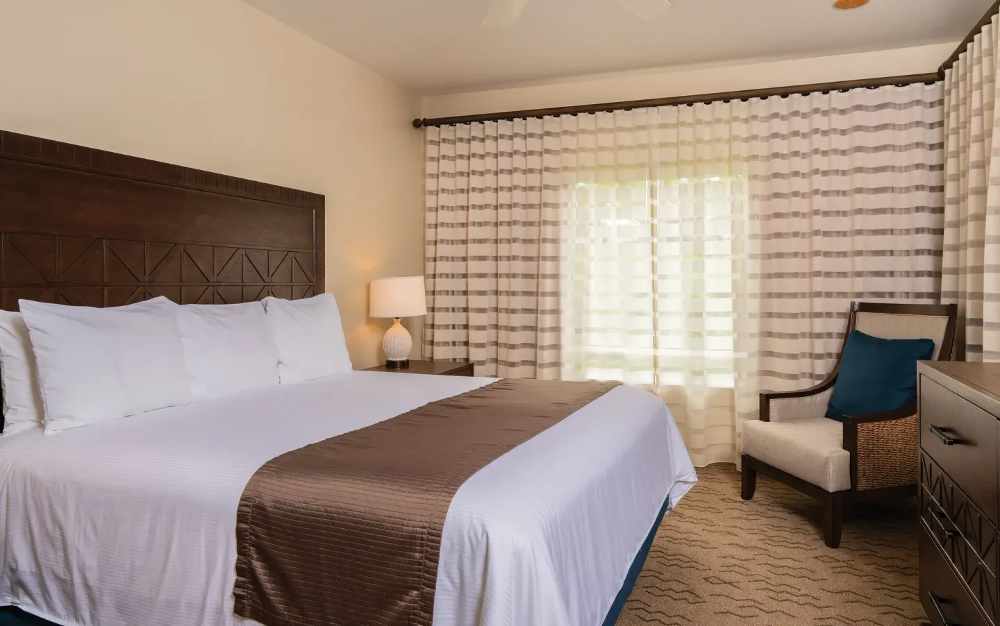 One Bedroom Villa Honu king bedroom with striped curtains at Kona Coast Resort.