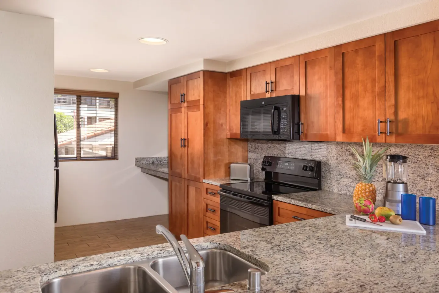 One Bedroom Villa Honu kitchen at Kona Coast Resort with double sink, granite counter, and black appliances.