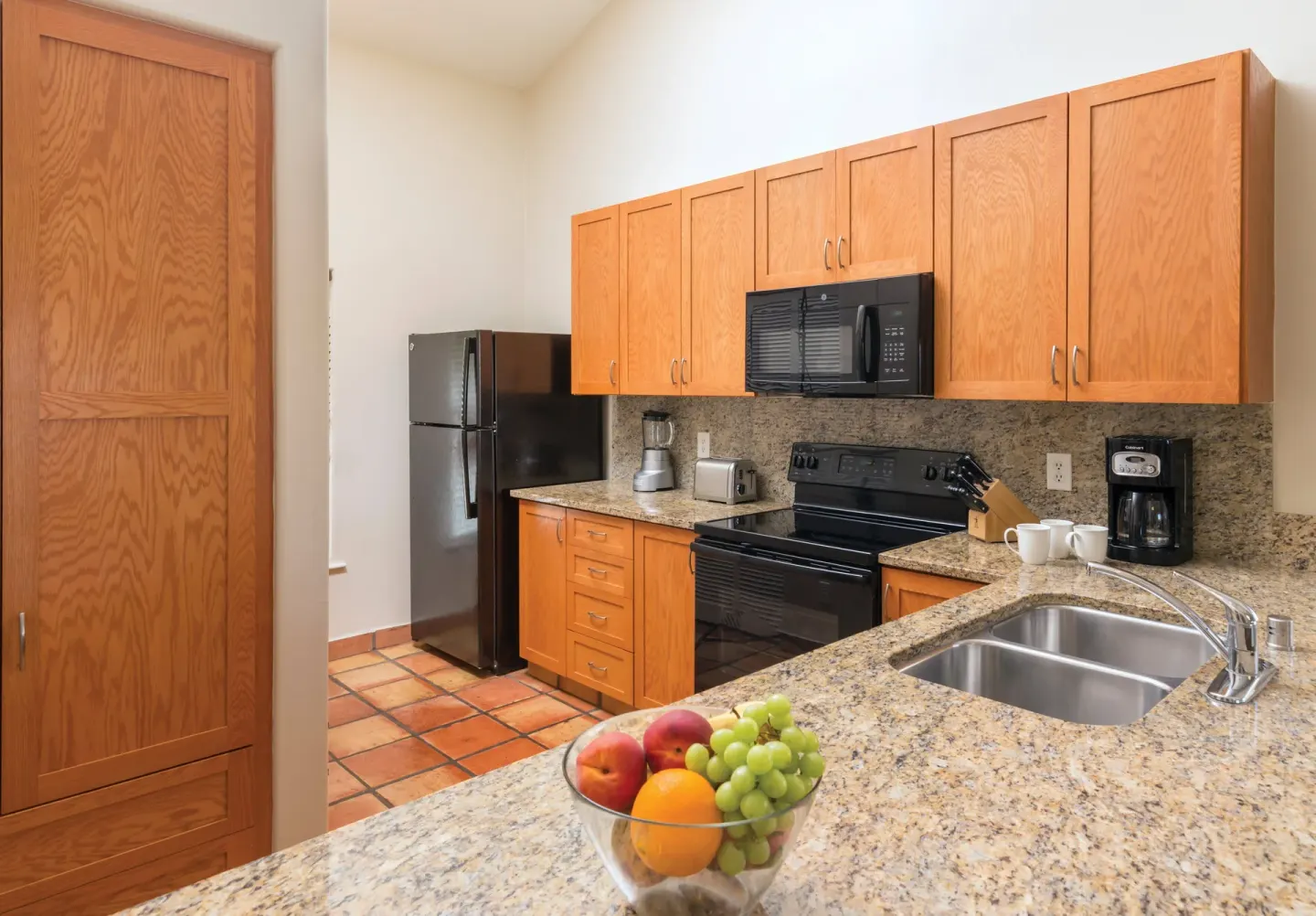 One Bedroom Villa Honu kitchen at Kona Coast Resort with refrigerator, granite island, and fruit bowl.