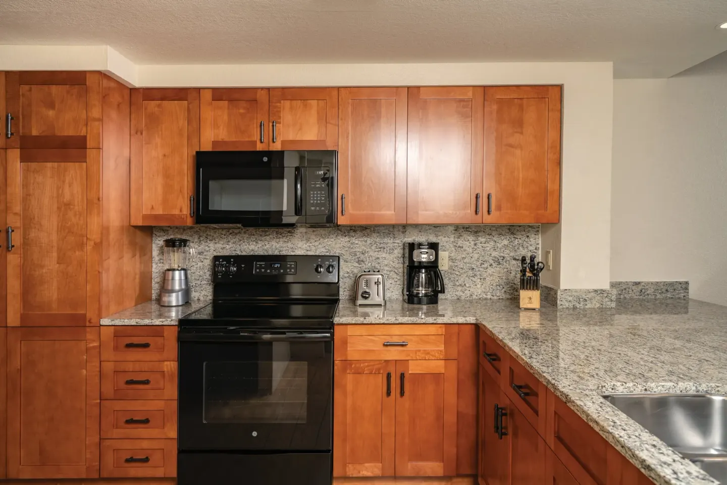 One Bedroom Villa Honu kitchen at Kona Coast Resort with wood cabinets, stove, microwave, and granite counters.