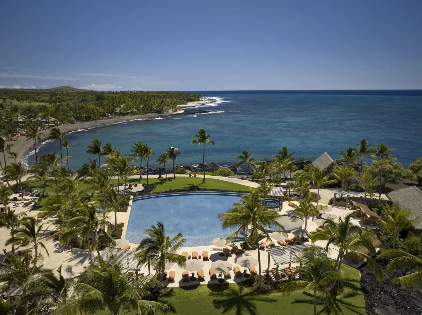 Aerial view of the pool, palms, coastline and blue ocean at Kona Village.