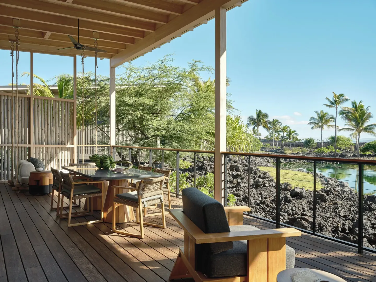 Covered lanai with dining table and lounge seating at Kona Village.