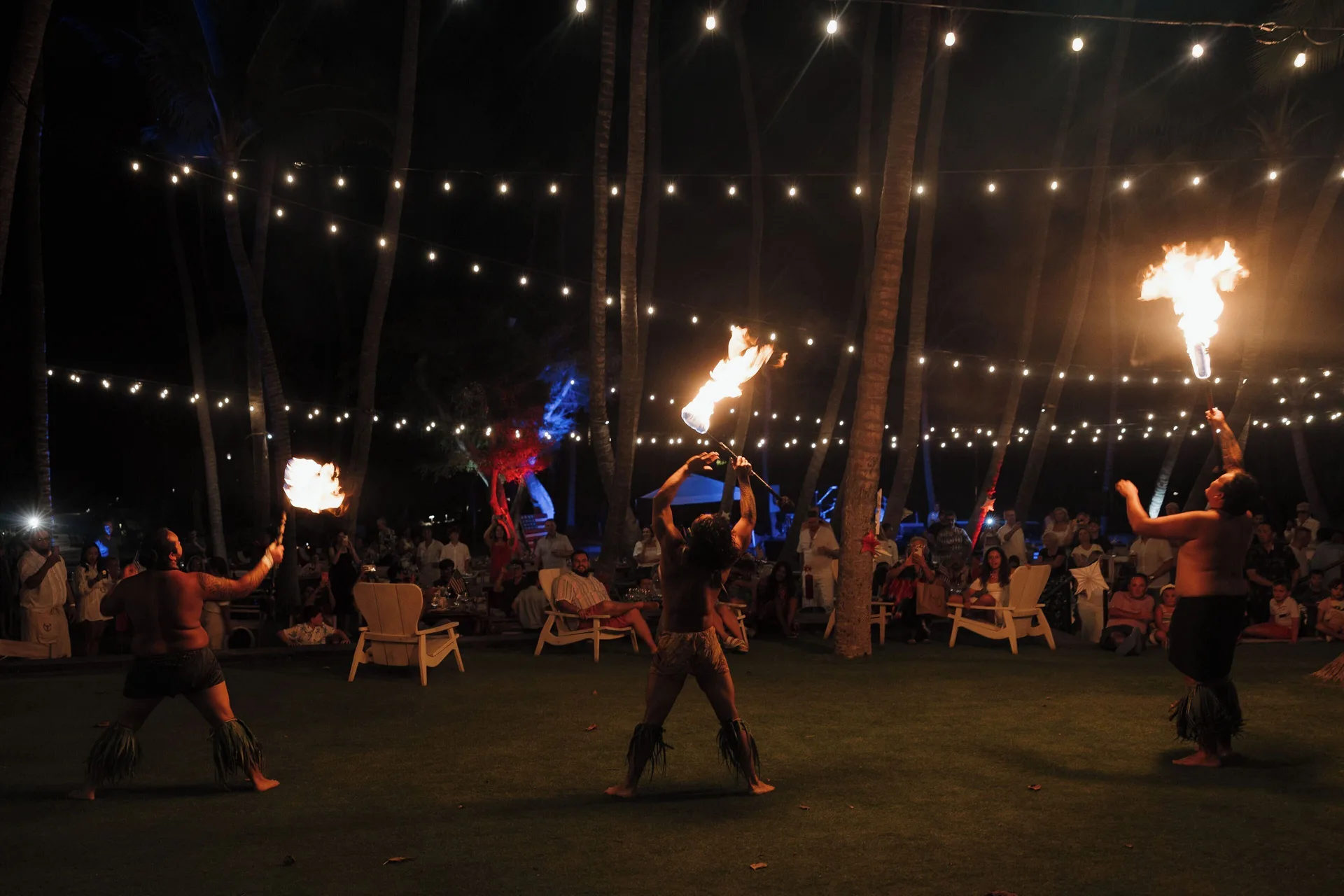 Fire performers entertain guests under string lights at night at Kona Village.