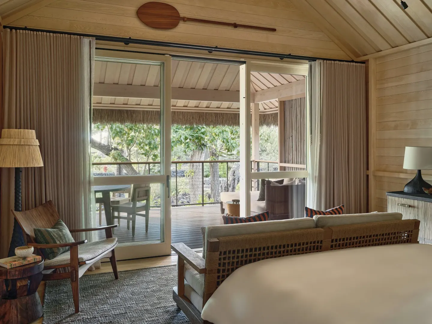 Guest room with king bed, sitting area, and lanai doors at Kona Village.