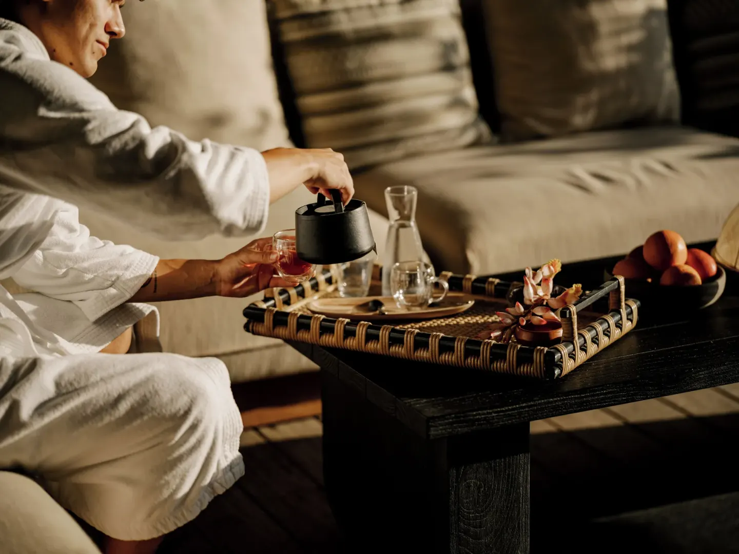 Guest in a robe pours tea at a lounge table at Kona Village.