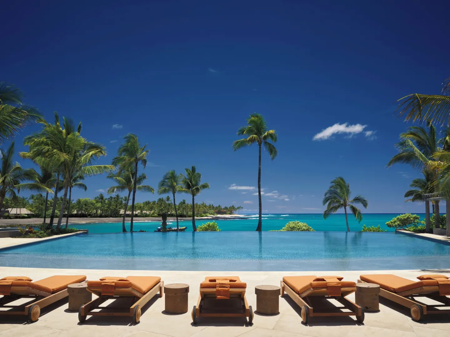 Infinity pool with ocean view and orange loungers at Kona Village.
