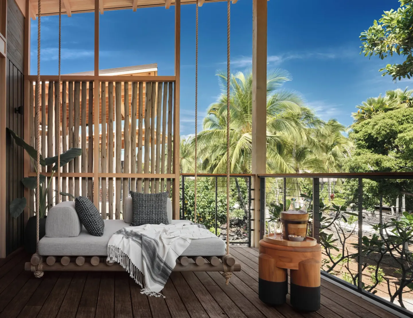 Covered lanai with daybed, drinks table, and palm views at Kona Village.