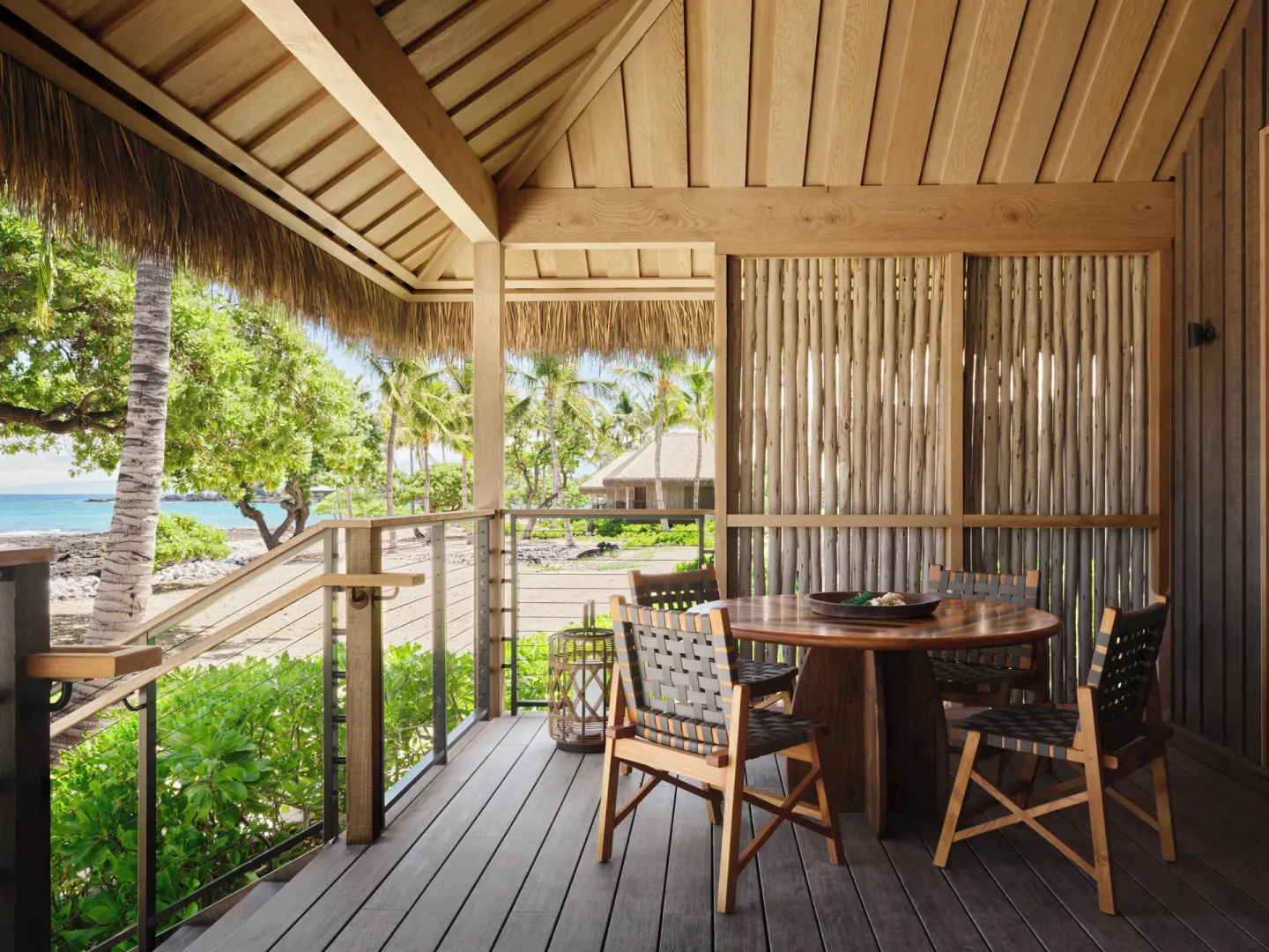 Covered lanai dining table with ocean and palm views at Kona Village.