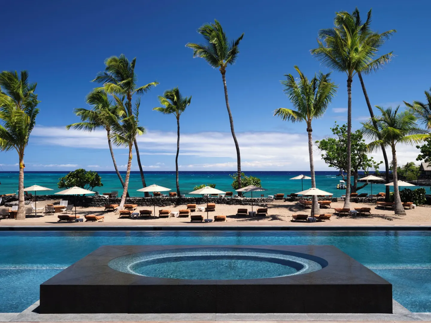 Oceanfront pool, beach loungers, palms and turquoise water at Kona Village.